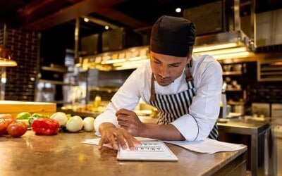 Chef in a commercial kitchen reviewing a menu on a tablet